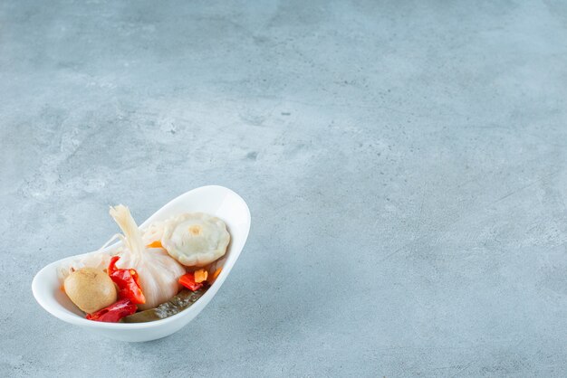 A bowl of mixed fermented vegetables on the blue surface