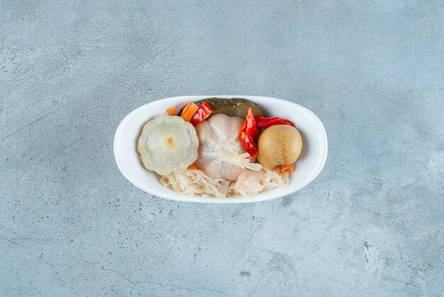 A bowl of mixed fermented vegetables on the blue surface