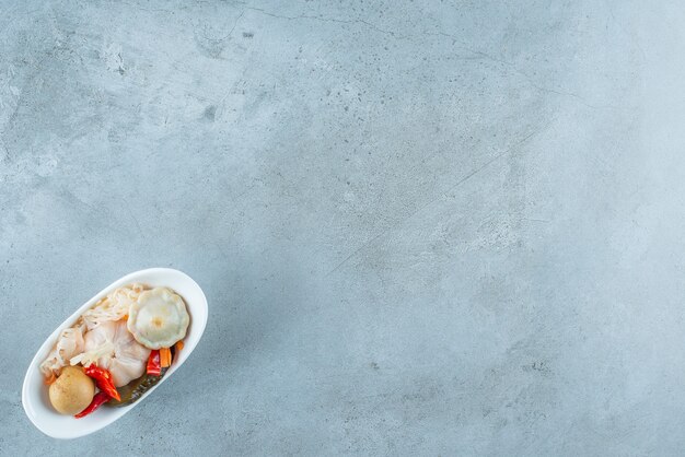 A bowl of mixed fermented vegetables , on the blue table. 