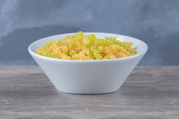 A bowl of mixed pasta , on the marble surface.