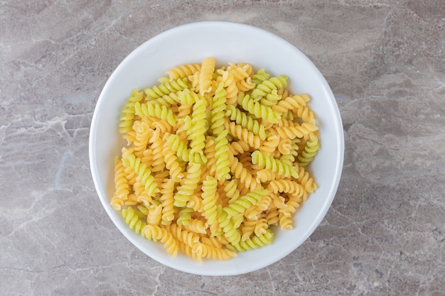 A bowl of mixed pasta , on the marble surface.