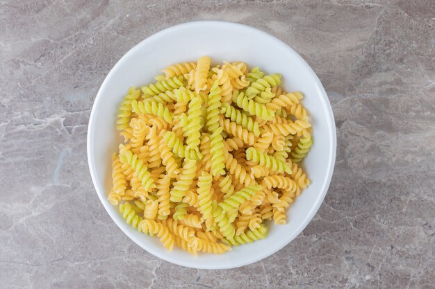 A bowl of mixed pasta , on the marble surface.