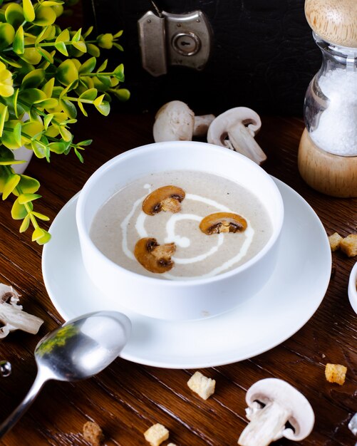 A bowl of mushroom soup garnished with cream and mushroom