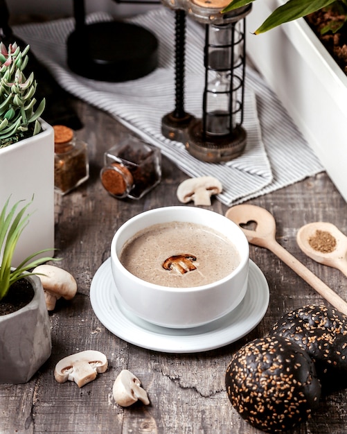 A bowl of mushroom soup served with black bread buns