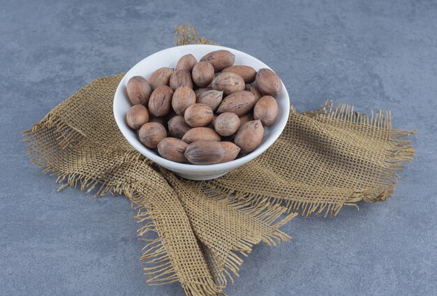 A bowl of nuts on the trivet, on the marble background. 