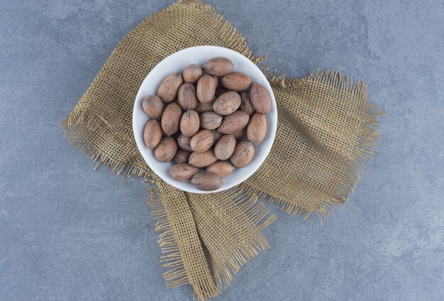 A bowl of nuts on the trivet, on the marble background. 