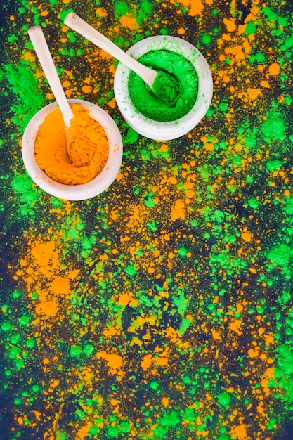 Bowl of an orange and green holi powder with spoon