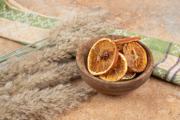 Bowl of orange slices with tablecloth on marble surface.