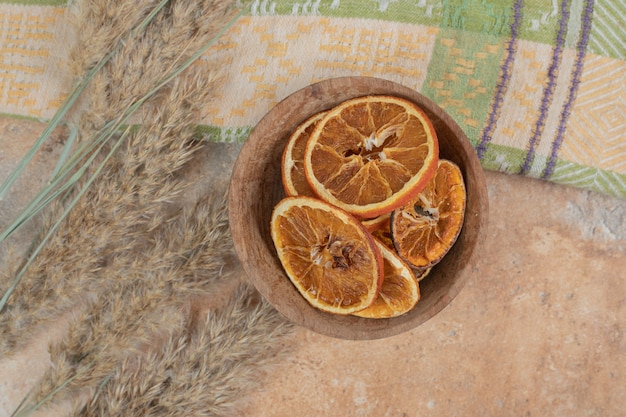 Bowl of orange slices with tablecloth on marble surface.