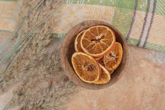 Bowl of orange slices with tablecloth on marble surface.