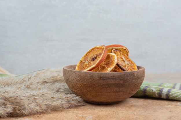 Bowl of orange slices with tablecloth on marble surface.