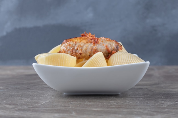 Una ciotola di pasta con bolognese, sulla superficie di marmo.