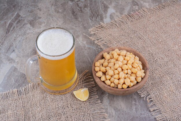 Bowl of peas and glass of beer on marble table. High quality photo