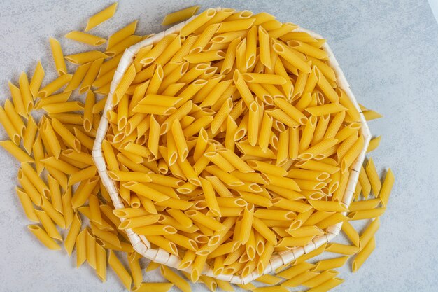 A bowl of penne pasta, on the marble.