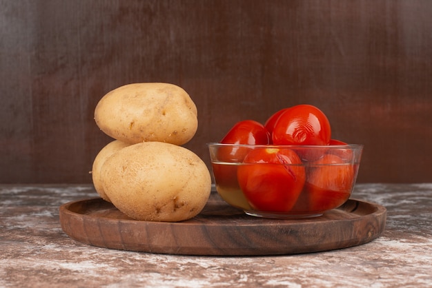 절인 된 토마토와 나무 접시에 삶은 감자 그릇.