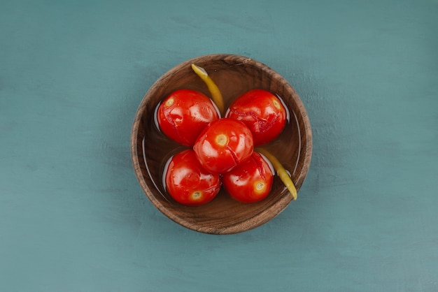 Bowl of pickled tomatoes on marble table.