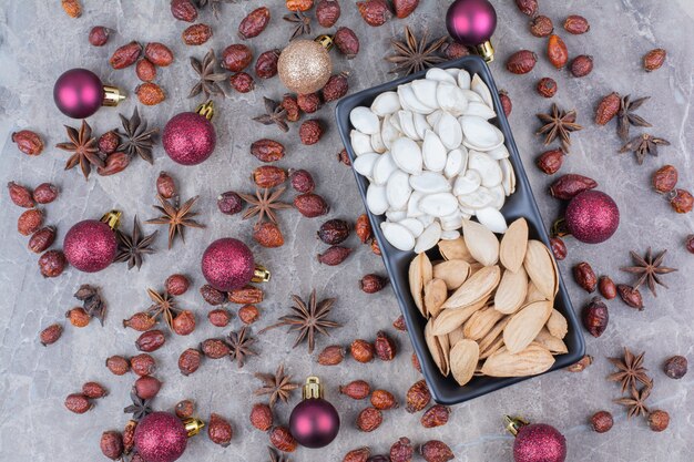 Bowl of pistachio and pumpkin seeds with rosehips and Christmas balls. 