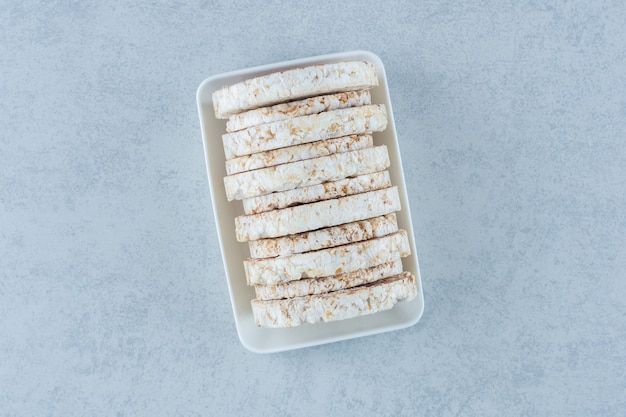 A bowl of puffed rice cakes on marble.