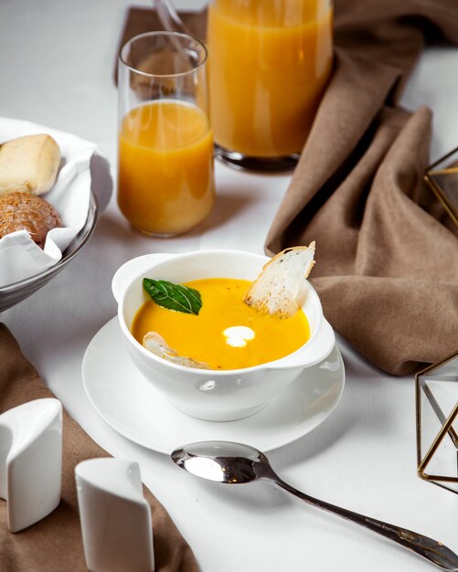 A bowl of pumpkin soup garnished with toast and cream