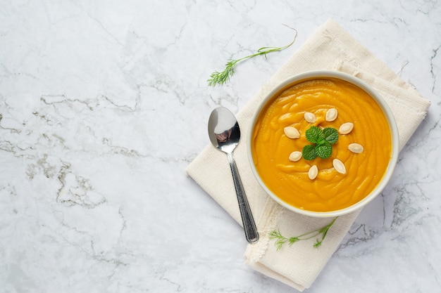 Bowl of pumpkin soup place on white fabric
