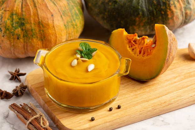 Bowl of pumpkin soup place on wooden cutting board