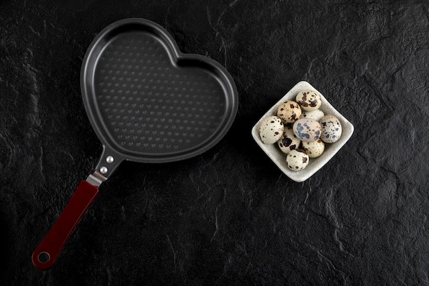 Bowl of quail eggs around empty heart shaped pan. 
