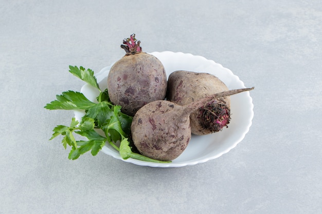 A bowl of radishes with parsley , on the marble background.