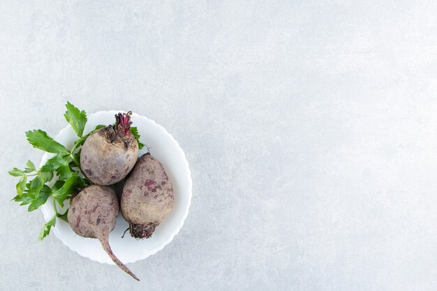 A bowl of radishes with parsley , on the marble.