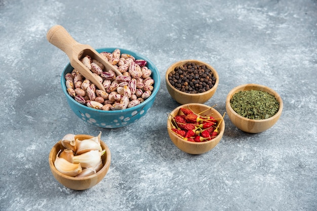 Bowl of raw beans and spices on marble background.