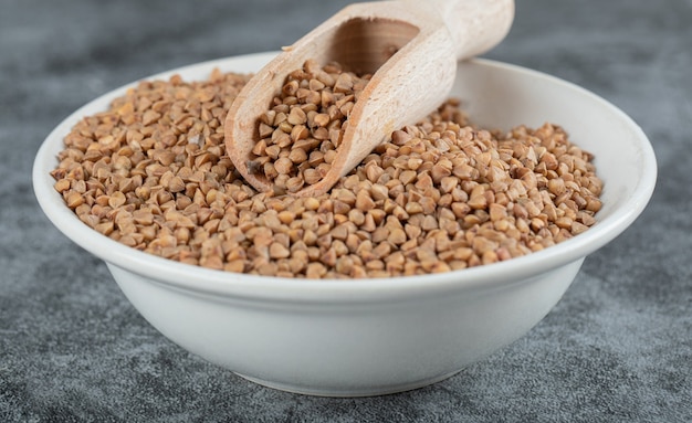 Bowl of raw buckwheat on marble surface