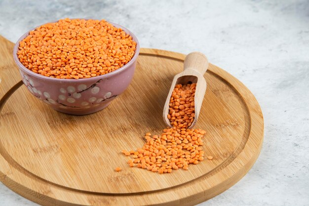 Bowl of raw lentils and spoon on cutting board.