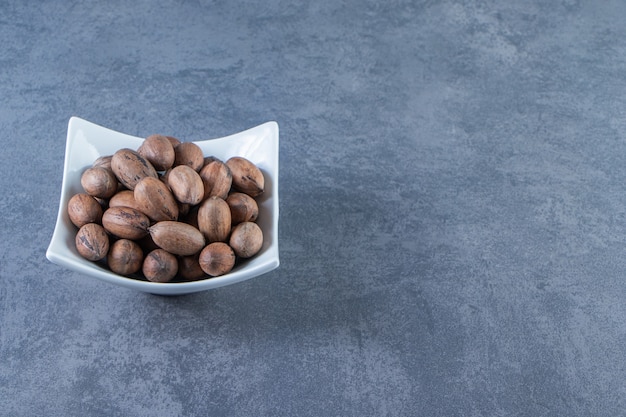 A bowl of raw nuts , on the marble background.