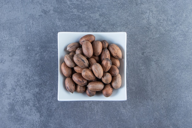 Free photo a bowl of raw nuts , on the marble background.