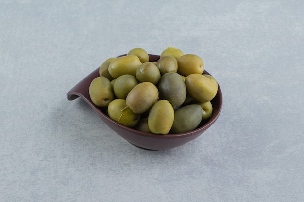 A bowl of raw olive on the marble surface