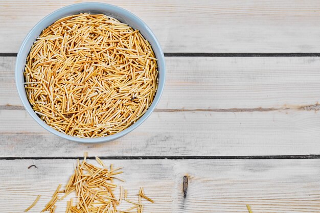 A bowl of raw pasta on wooden table