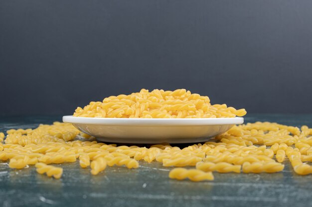 Bowl of raw spiral pasta on blue background. High quality photo