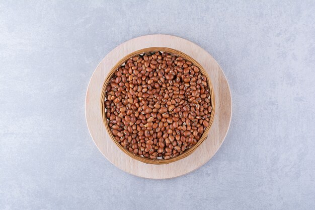 Bowl of red beans placed on a wooden platter on marble surface