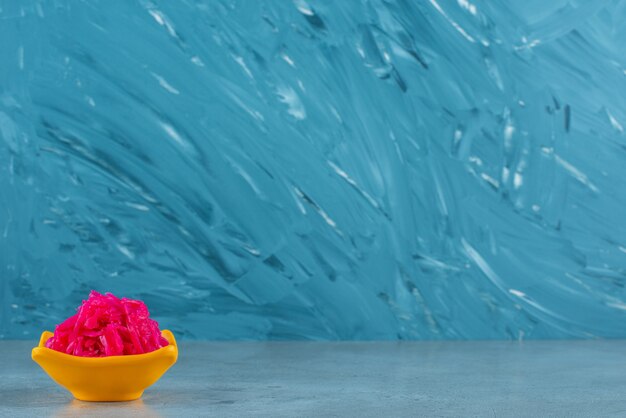 A bowl of red sauerkraut, on the blue table. 