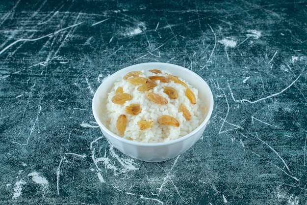 A bowl of rice pudding with raisins , on the blue background. High quality photo