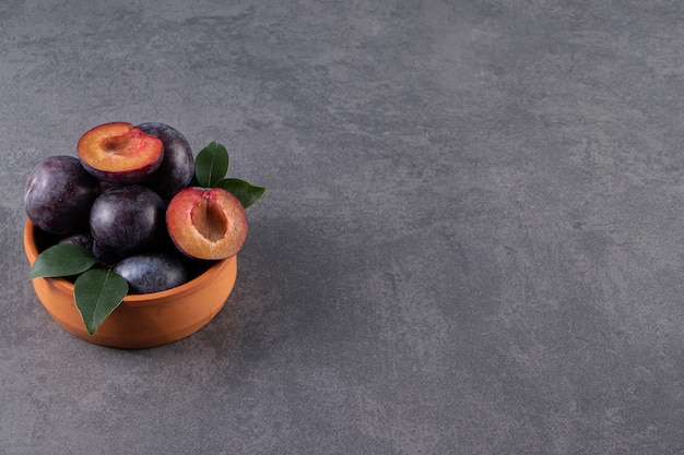 Free photo a bowl of ripe plum , on the marble table.