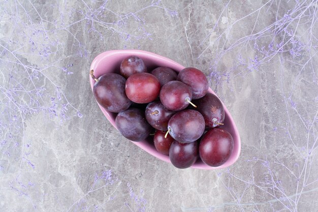 Bowl of ripe plums on stone background. 