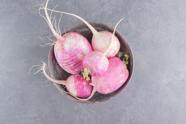 A bowl of ripe radishes on the marble surface