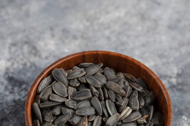 Free photo bowl of roasted black sunflower seeds on white surface