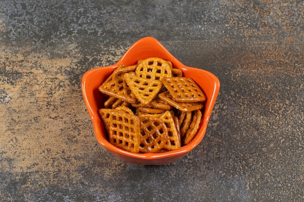 Bowl of salted crackers on marble surface. 