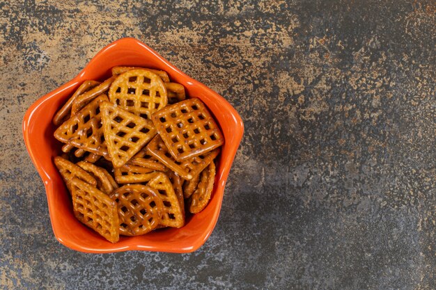 Bowl of salted crackers on marble surface. 