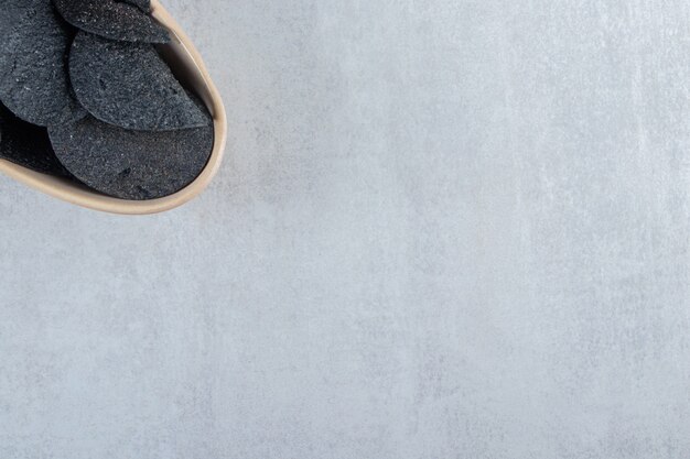 Bowl of salted crispy black chips on stone.