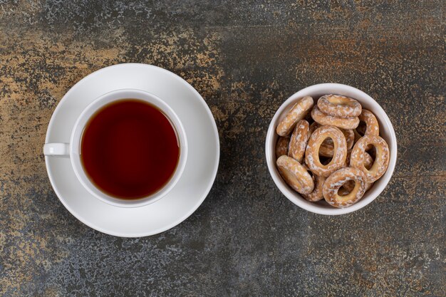 Bowl of salty crackers and cup of tea on marble.