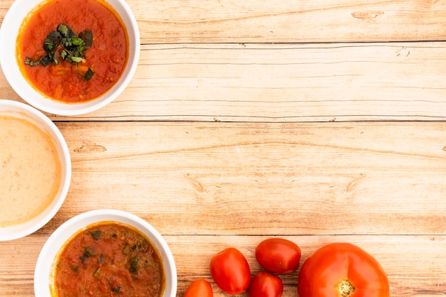 Bowl of sauces and fresh tomatoes on wooden table