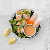 Free photo bowl of shrimp rolls with sauce and lemon slices