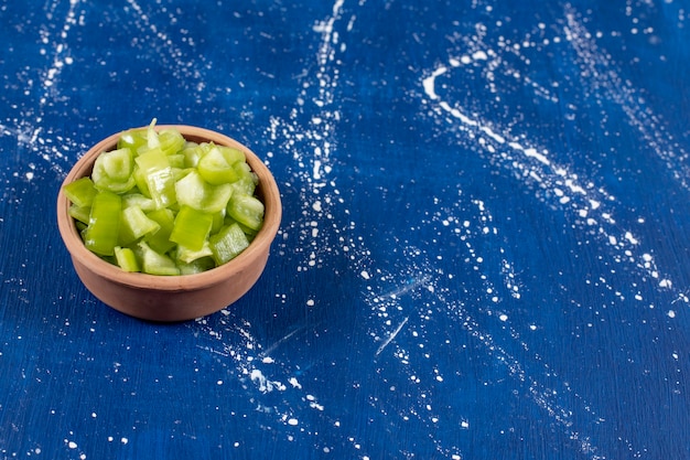 Bowl of sliced green bell peppers on marble surface. 